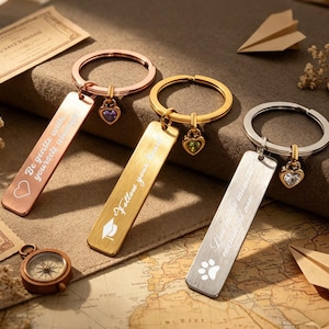 Può includere: Tre portachiavi in metallo con targhette rettangolari e piccoli ciondoli a forma di cuore. La targhetta in oro rosa reca la scritta Be gentle with yourself always, quella dorata Follow your heart e quella argentata Live in the moment.