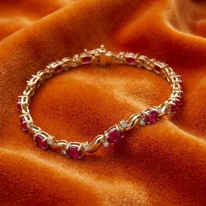 May include: A gold link bracelet featuring a series of oval-cut red rubies alternating with small round white diamonds. The bracelet is constructed with polished gold metal links connecting each gemstone setting and includes a secure box clasp closure.