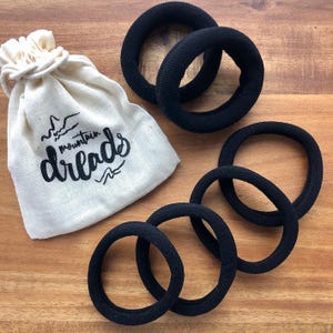 May include: A set of six black hair scrunchies with a small white fabric bag that says "mountain dreads".