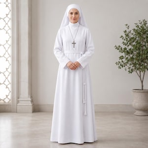Może przedstawiać: Biały habit do ziemi z długimi rękawami, wysokim dekoltem i pasującym białym paskiem w talii z frędzlami na końcach. Srebrny wisiorek w kształcie krzyża wisi na łańcuszku na szyi, a białe nakrycie głowy opada na ramiona.