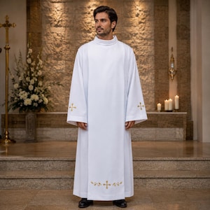 May include: A floor-length white alb featuring long sleeves and a high round neckline. The garment is decorated with gold embroidered cross motifs on each sleeve cuff and a larger gold embroidered cross with leaf accents at the bottom center.
