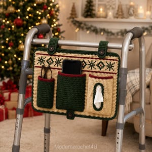 May include: A beige and dark green crochet walker bag with a festive snowflake pattern, featuring three pockets holding glasses, a smartphone, and tissues. The bag attaches to a metal walker with two dark green straps and dark brown buttons.