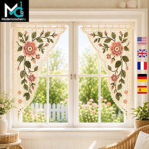 May include: A pair of cream-colored crochet curtains featuring a triangular shape with an intricate floral pattern. The design includes large pink flowers, smaller pink buds, and dark green leaves arranged on a delicate, open-work mesh background.