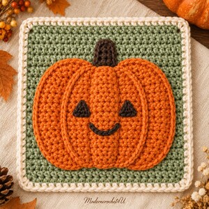 May include: A square crochet granny square featuring a central orange pumpkin with a dark brown stem and a smiling jack-o'-lantern face. The pumpkin is set against a sage green background, framed by a cream-colored border. The text Moderncrochet4U is visible.