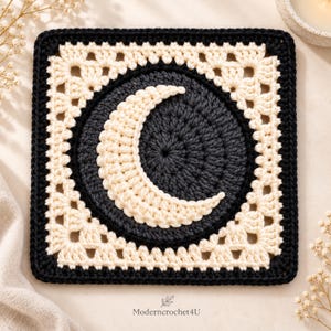 May include: A square crochet motif featuring a dark charcoal gray circular center with a cream-colored crescent moon design. The square is framed by a cream-colored lacy border and finished with a solid black outer edge. Text reads Moderncrochet4U.