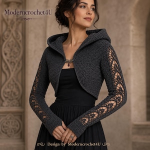 May include: A dark gray hooded crochet bolero featuring long sleeves with intricate openwork lace patterns. The garment is secured at the front with a single decorative metal clasp featuring a small dark red stone. The text Moderncrochet4U is visible.