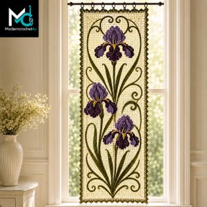 Puede incluir: Un colgante de ventana rectangular de ganchillo que presenta tres flores de iris moradas con tallos y hojas verdes sobre un fondo de malla color crema. La pieza está bordeada por un borde festoneado verde oscuro y cuelga de una barra negra.