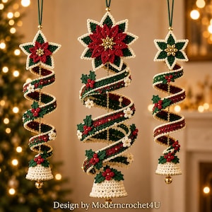 Op de afbeelding: Drie hangende gehaakte ornamenten met een spiraalontwerp in rood, groen en crème. Elk ornament is bekroond met een ster en eindigt onderaan met een bel, versierd met kleine bloemen en hulstbessen. Tekst luidt: Design by Moderncrochet4U.