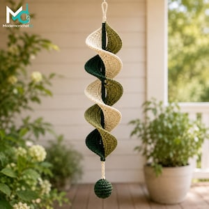 May include: A hanging spiral decoration crafted from crocheted yarn in alternating shades of cream, olive green, and dark forest green. The structure features a central vertical cord ending in a solid, spherical crocheted ball at the bottom.