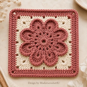 May include: A square crochet motif featuring a central dusty rose flower with eight rounded petals, surrounded by a cream-colored square border and an outer dusty rose frame. The text "Design by Moderncrochet4U" is printed at the bottom.