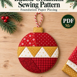 May include: A Scrappy Christmas Bauble Ornament sewing pattern for foundation paper piecing in 5 & 6 inch sizes. The circular ornament features red, white, and gold fabric patches with floral, polka dot, and star patterns, topped with a gold cap and red and white striped hanging loop.