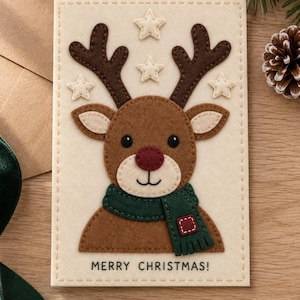 Può includere: Un biglietto d'auguri rettangolare con uno sfondo in feltro color crema che presenta un'applicazione di renna marrone con corna marrone scuro, un naso rosso e una sciarpa verde scuro. Il biglietto include quattro stelle crema e il testo MERRY CHRISTMAS!