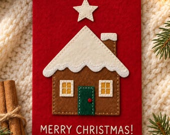May include: A red greeting card featuring a felt gingerbread house applique with a white roof, a green door, and two yellow windows. A white felt star sits above the house. The text MERRY CHRISTMAS! is printed in white at the bottom of the card.