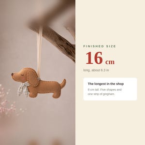 May include: A brown felt dachshund ornament with a light blue and white gingham scarf, hanging from a ribbon. Text indicates a finished size of 16 cm long, 6.3 inches, and 8 cm tall, noting it is the longest in the shop with five shapes.