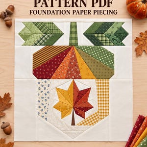 Peut inclure: Un patron de courtepointe représentant un motif de gland avec une feuille d'érable centrale. Le texte indique ACORN QUILT PATTERN PDF FOUNDATION PAPER PIECING et 10 12 14 inches. Le design utilise divers tissus aux tons verts, rouges et jaunes.