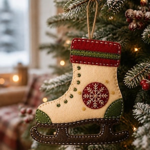 May include: A felt ice skate ornament featuring a cream-colored boot with a red cuff, green toe and heel accents, and a dark brown blade. The side of the boot is decorated with a circular red patch featuring a white embroidered snowflake design.