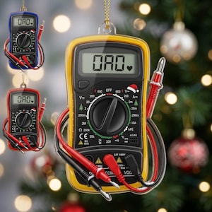 May include: A flat, ornament-style digital multimeter featuring a yellow, red, or blue protective casing. The screen displays the text OAO with a heart symbol. It includes a rotary dial, input ports, and attached red and black test leads.
