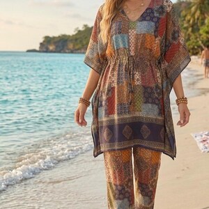 Op de afbeelding: Een tweedelige outfit bestaande uit een tuniek met V-hals en een trekkoord in de taille en een bijpassende broek met rechte pijpen. De set heeft een veelkleurig patchworkpatroon in bruin-, blauw-, oranje- en groentinten met een donkere zoom.