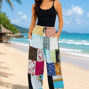 May include: A black sleeveless vest top paired with loose-fitting, ankle-length trousers featuring a multi-coloured patchwork design. The trousers include various floral, geometric, and solid patterns in shades of blue, pink, yellow, and black, with a drawstring waist.
