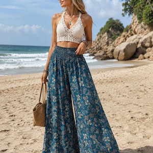 Peut inclure: Un haut dos nu en crochet de couleur crème associé à un pantalon taille haute à jambes larges en tissu bleu sarcelle foncé avec un imprimé floral et cachemire multicolore. Le pantalon possède une taille élastique froncée et une coupe fluide.