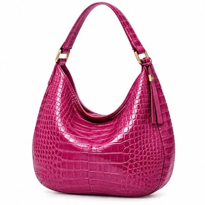 Könnte beinhalten: Eine leuchtend fuchsiafarbene Hobo-Tasche mit einer glänzenden, geprägten Krokodilleder-Textur. Die Tasche hat einen einzelnen Schulterriemen mit goldfarbenen Metallbeschlägen und ein passendes Lederquasten-Detail an der seitlichen Befestigung.