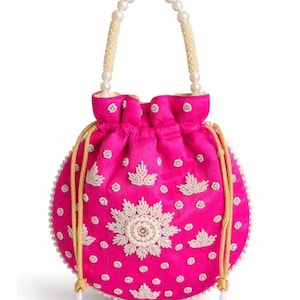 Peut inclure: Un sac bourse fuchsia vif doté de perles blanches complexes formant des motifs floraux et étoilés. Le sac comprend une anse en perles blanches et des cordons de serrage tressés dorés avec des pompons terminés par des perles aux extrémités.