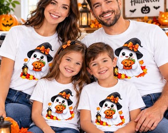 May include: White short-sleeve t-shirts featuring a graphic of a cartoon ghost wearing a black witch hat with an orange bow, holding a jack-o'-lantern pumpkin, surrounded by autumn leaves and a small lantern, paired with blue denim jeans.