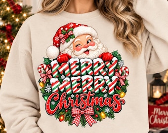 May include: A beige crewneck sweatshirt featuring a graphic of a winking Santa Claus wearing a red hat. Below the Santa, the text reads Merry Merry Christmas in red and green candy cane striped lettering, surrounded by a wreath with a red plaid bow.