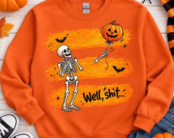 May include: An orange crewneck sweatshirt featuring a graphic of a skeleton holding a pumpkin balloon. The design includes spider web patterns, bats, and the text "Well, shit...." printed in black. The sweatshirt has long sleeves and a ribbed collar.