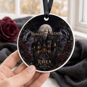 Peut inclure: Une décoration en céramique ronde illustrant un manoir gothique sous une pleine lune, avec le texte Midnight at the Manor, Raven et 2026-07-24. Le motif inclut des arbres sombres, des corbeaux et des roses rouge foncé, avec un ruban noir.