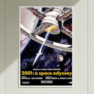 以下が含まれることがあります： 映画『2001年宇宙の旅』のポスター。惑星の軌道上に浮かぶ巨大な白い宇宙ステーションと、暗い星空の中をステーションに向かって飛行する小さな白い宇宙船が描かれている。下部には黄色の文字でタイトルが記されている。