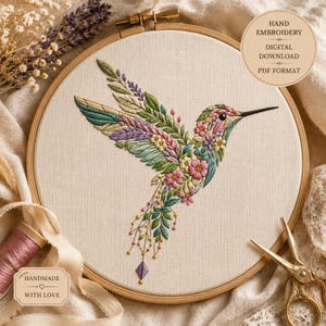 May include: A hummingbird embroidery design on off-white fabric in a wooden hoop. The bird is composed of green, pink, and purple floral and leaf patterns. Text on the image reads: HAND EMBROIDERY DIGITAL DOWNLOAD PDF FORMAT and HANDMADE WITH LOVE.