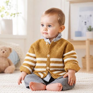 May include: A mustard yellow knit cardigan featuring horizontal white stripes on the sleeves and torso, a button-down front with light-coloured buttons, and a collared light blue and white pinstriped shirt worn underneath with grey trousers.