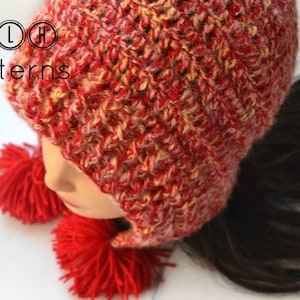 May include: Red and yellow crocheted hat with ear flaps and two red pom-poms. The hat is made with a textured stitch and has a slouchy fit.