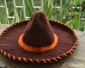 Puede incluir: Un sombrero de crochet marrón con ribete naranja y una corona de crochet marrón. El sombrero tiene un borde naranja cosido alrededor del borde.