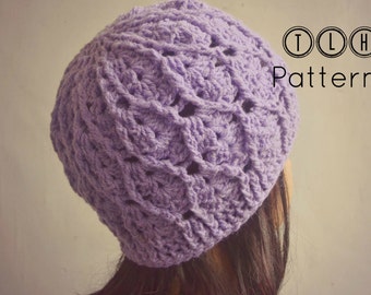 May include: A purple crocheted hat with a textured pattern. The hat is worn on a person's head. TLH Patterns.