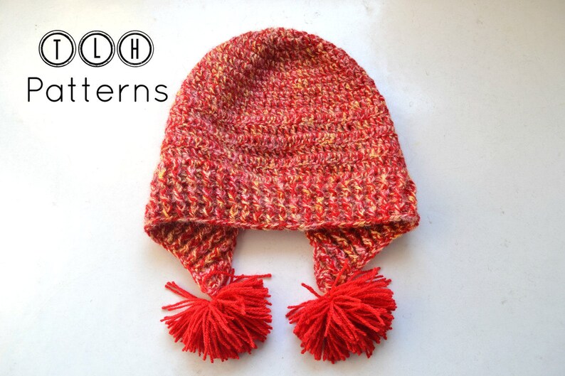 May include: Red and yellow crocheted hat with two pom-poms on the ends of the ear flaps. TLH Patterns.