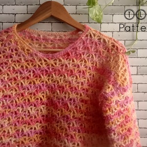 May include: A crocheted sweater in a multi-colored ombre pattern of pink, orange, and yellow. The sweater has a loose, open-weave design and a round neckline.