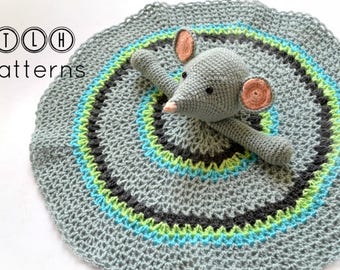 May include: A gray crocheted baby blanket with a gray crocheted mouse toy in the center. The blanket has blue, green, and black stripes around the edge.