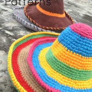 Pode incluir: Dois chap&eacute;us de croch&ecirc;, um marrom com uma faixa laranja e outro com listras coloridas. Os chap&eacute;us est&atilde;o sobre uma superf&iacute;cie de pedra cinza.