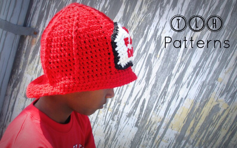 May include: A red crocheted firefighter hat with a black and white "Fire Dept" patch. The hat has a wide brim and is being worn by a child.
