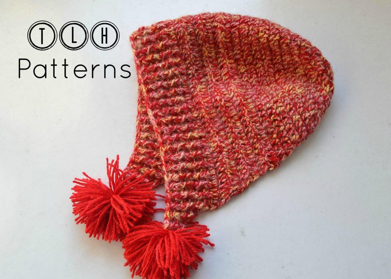May include: Red and yellow crocheted hat with a pom-pom on the end. TLH Patterns.