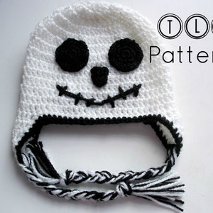 May include: White crocheted hat with a black crocheted face, featuring two eyes, a nose, and a stitched mouth. The hat has a black and white braided tassel.