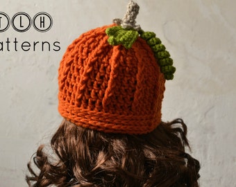 May include: A crocheted pumpkin hat in orange with a green stem and leaves. The hat is worn on a person with brown curly hair. The text "TLH Patterns" is visible in the top left corner of the image.