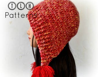 Puede incluir: Un gorro de punto rojo y amarillo con un largo borde puntiagudo y un borla roja. El gorro lo lleva una persona con el pelo largo y oscuro.