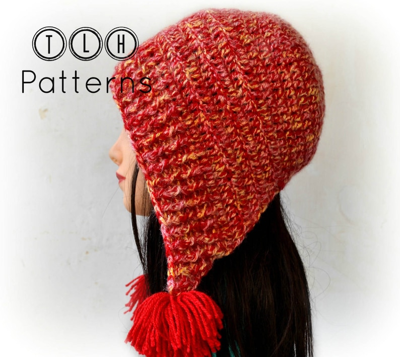 May include: A red and yellow crocheted hat with a long pointed brim and a red tassel. The hat is worn by a person with long dark hair.