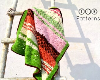 May include: A multi-colored crocheted blanket with stripes of green, white, pink, brown, and orange. The blanket is draped over a wooden ladder against a white wall. The text "TLH Patterns" is visible in the upper right corner of the image.