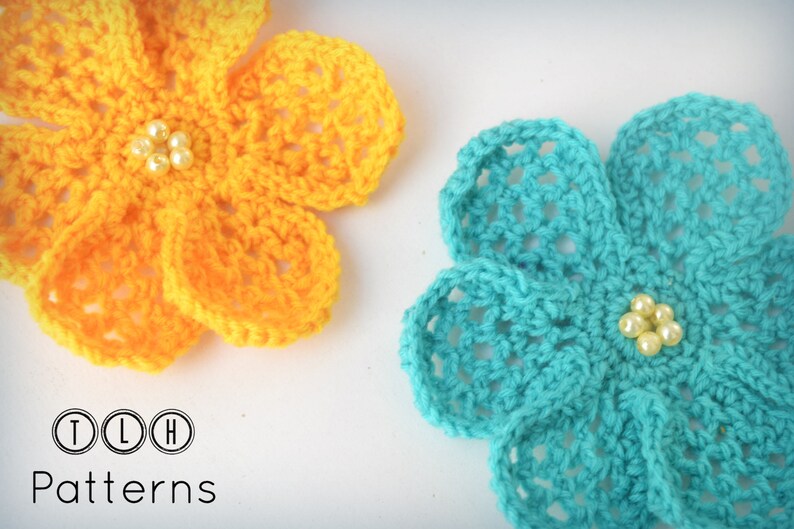 May include: Two crocheted flowers, one yellow and one turquoise, with pearl beads in the center. TLH Patterns.