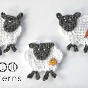 Op de afbeelding: Drie handgemaakte gehaakte schapen met witte wol en grijze gezichten en poten. Elk schaap heeft een knoop in de vorm van een hart in blauw, oranje of bruin. De tekst "TLH Patterns" staat onderaan.