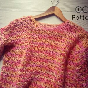 May include: A crocheted sweater in a pink, orange, and white color scheme. The sweater has a loose, open-weave design and a round neckline.